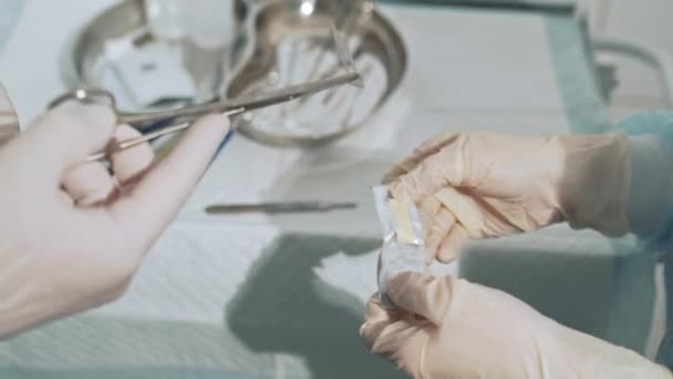 Chirurgische tafel met steriele medische instrumenten. De assistent geeft de chirurg het scalpel blad. Close-up shot van artsen handen met chirurgische leveringen. Begrip gezondheid, teamwerk in het ziekenhuis. — Stockvideo