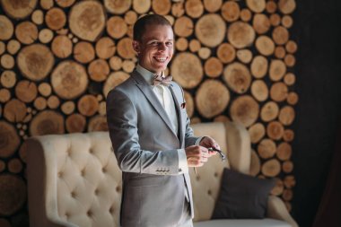 Gülümseyen bir damat düğün gününde hazırlanır, bir ceket koyar ve kolları düzeltiyor. Klasik iş elbiseleri iş ya da ofis için. İşadamı gri takım elbise ve beyaz gömlek.