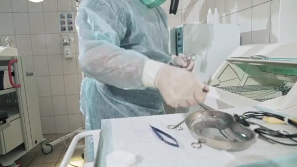 Крупним планом, хірург, який працює в лікарні, дезінфікує медичні інструменти перед операцією. Доктор в окулярах, професійний одяг, стерильна маска та плаття. Поняття здоров'я — стокове відео