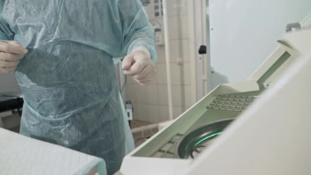 Primo piano, il chirurgo che lavora in ospedale disinfetta gli strumenti medici prima dell'intervento. Dottore in occhiali, vestiti professionali, una maschera sterile e vestaglia. Il concetto di salute — Video Stock