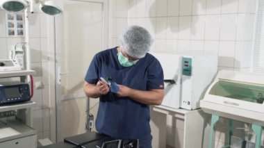 Klinikte doktor elinde tıbbi malzeme vardır. Tanı Cihazları cerrahi odasında. Cerrah adam hastanede ameliyat için hazırlar, gözlük koyar. Steril ekipmanları ve