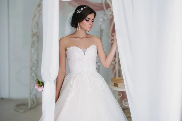 Ochtend van de bruid. Portret van mooie vrouw in witte luxe trouwjurk met bruids make-up en kapsel. Geweldig model slijtage diamanten juwelen in het haar. — Stockfoto