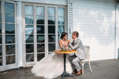 masada oturan ve sarılma yeni evliler. Gelin ve damat birbirine bakarak. Bir adam bir gri takım elbise, beyaz bir gömlek ve bir papyon. Beyaz elbiseli bir düğün makyajlı genç kız ve