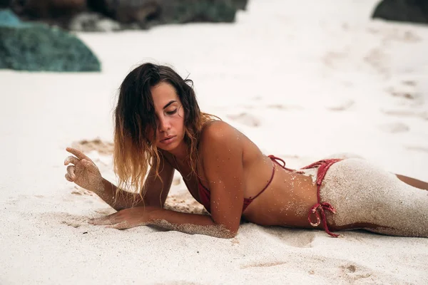 Modello sexy si trova sulla spiaggia con il culo nella sabbia. Una ragazza abbronzata con una figura sexy sta riposando all'estero in mare. Bellissimo corpo di una giovane donna . — Foto Stock