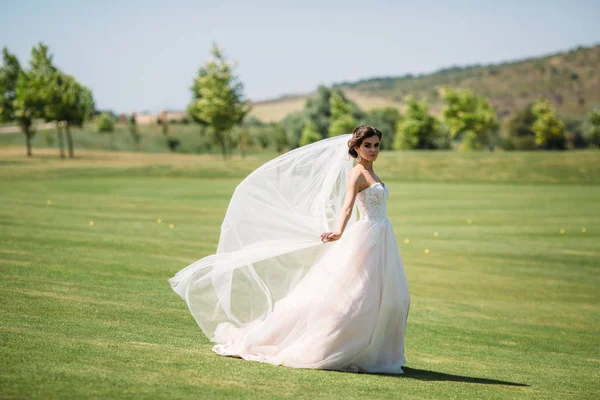 Schöne Braut in luxuriöser Mode weißes Hochzeitskleid mit Schleier auf der grünen Golfclub Lichtung, Hochzeitstag. erstaunliche Ganzkörperporträt von Mädchen. Ehekonzept. — Stockfoto