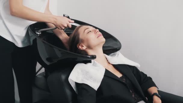 Close-up hand van kapper wast haar naar jonge vrouw in schoonheidssalon — Stockvideo