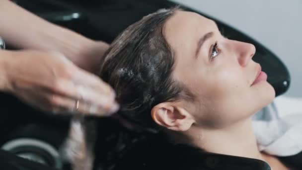 Gros plan main de coiffeur lave les cheveux avec shampooing pour femme dans le salon de beauté — Video