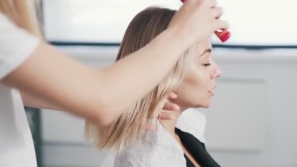Kuaförün ellerini kapat. Saç bakımı prosedüründen önce kadının ıslak saçlarını tara. — Stok video