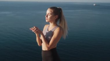 Kadın egzersizleri yapar ve deniz manzarası ile gün doğumunda uzanır, yavaş hareket