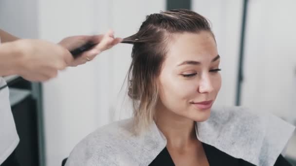 若い女性の髪に髪のマスクを適用する美容師の手の閉じる — ストック動画
