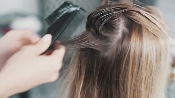 El primer plano de las manos de peluquero aplicando la máscara para el cabello en el cabello de la mujer joven — Vídeos de Stock