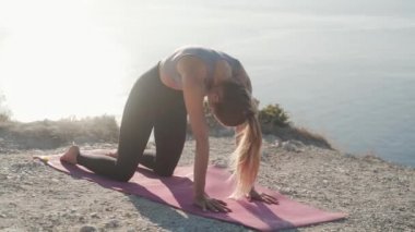 Kadın yoga egzersizleri yapar ve deniz manzarası ile sabah uzanır, yavaş hareket