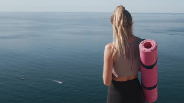 Vista trasera de la chica atleta mirando el teléfono en sus manos, océano en el fondo — Vídeos de Stock