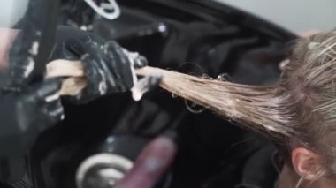 Kapat, kuaför müşterinin saçını tarar ve kuaföre saç boyası sürer.