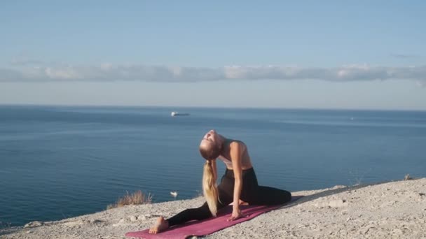 Mujer haciendo ejercicio de yoga en la cima de la montaña, mar sobre fondo, cámara lenta — Vídeo de stock