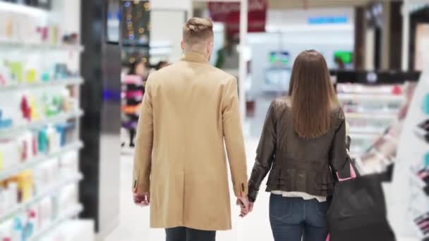 Visão traseira, homem e mulher vão às compras de mãos dadas, steadicam tiro — Vídeo de Stock