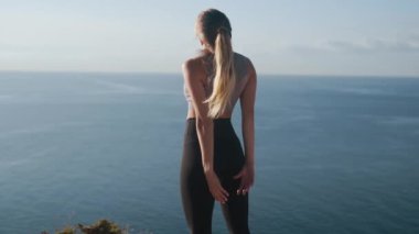 Kadın egzersizler yapar ve sabah uzanır, arka planda deniz, yavaş hareket