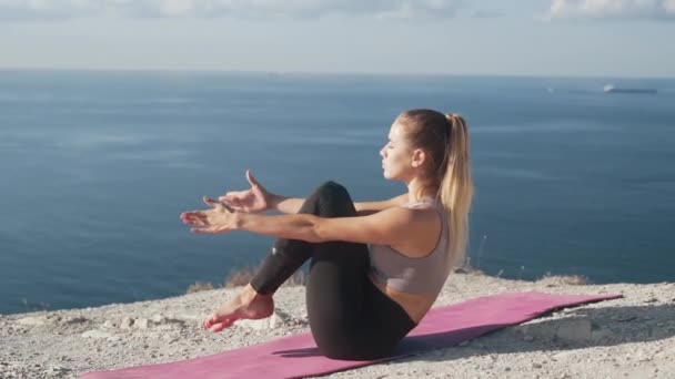 Женщина делает упражнения и растяжки по утрам с видом на море, замедленная съемка — стоковое видео