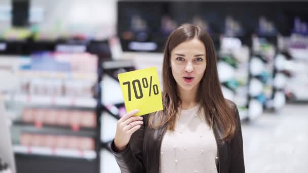 Mujer en la tienda de cosméticos muestra el pulgar hacia arriba y signo de descuento, gran venta, se sorprendió — Vídeos de Stock