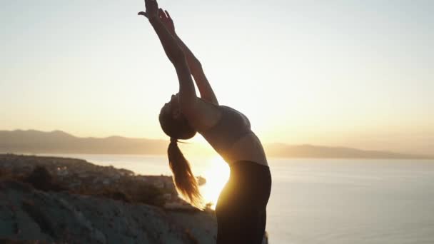 Silhouette de la femme faisant des étirements tôt le matin dans le rayon de soleil, au ralenti — Video