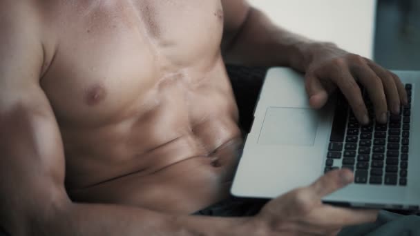 Close up, shirtless man with sexy body sits in chair outdoor and works on laptop — Stock Video