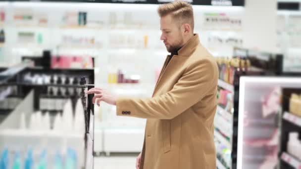 Giovane bell'uomo sceglie le merci nel negozio di cosmetici, concetto di shopping — Video Stock