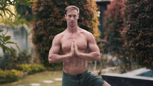 Ritratto di uomo senza maglietta con corpo muscolare che fa esercizi di yoga in giardino — Video Stock