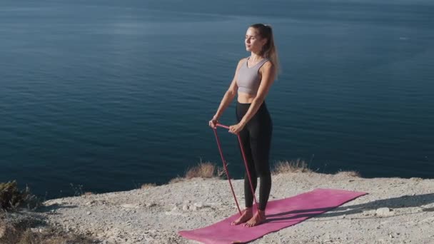 Vrouw maakt training met elastiekjes in de buitenlucht, traint haar lichaam, Slow Motion — Stockvideo