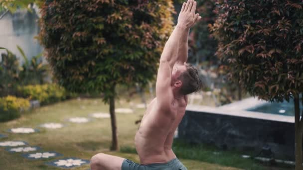 Retrato de hombre sin camisa con cuerpo muscular haciendo ejercicios de yoga en el jardín — Vídeos de Stock