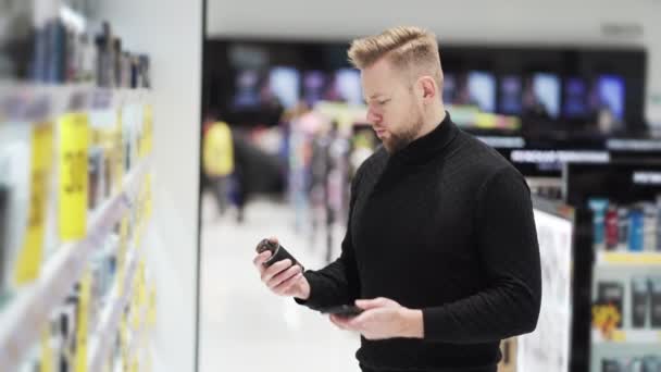 Jovem usa telefone e tira foto de mercadorias na loja de cosméticos — Vídeo de Stock