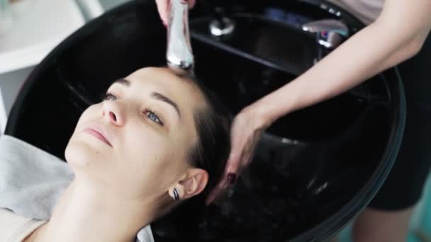 Gros plan main de coiffeur lave les cheveux à la femme dans le salon de beauté — Video