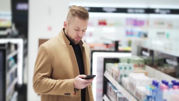 Giovane uomo barbuto utilizza il telefono cellulare e chatta online nel centro commerciale — Video Stock