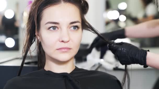 Закройте, руки парикмахера наносят кератин на волосы женщины — стоковое видео
