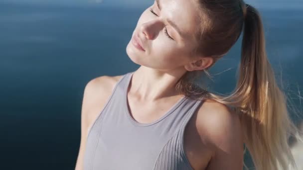 Retrato de la mujer hace ejercicios de estiramiento al amanecer, vista sobre el mar en el fondo — Vídeo de stock