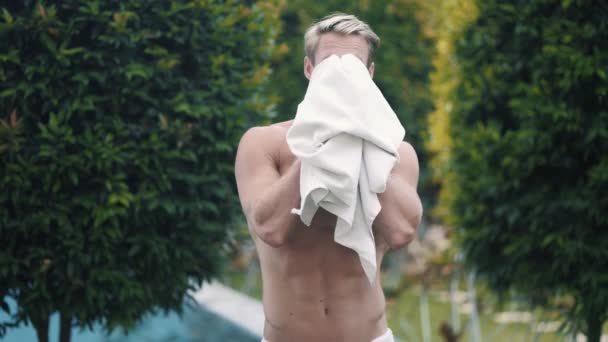 Shirtless sexy man wipes his face and body with towel after swimming in pool — Stock Video