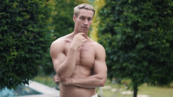 Portrait of handsome shirtless man posing on camera, greenery on background — Stock Video