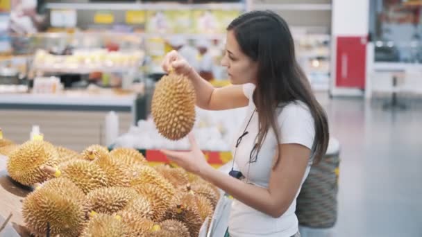 Jeune femme touristique choisit des fruits mûrs dans l'épicerie, renifle et prendre un — Video