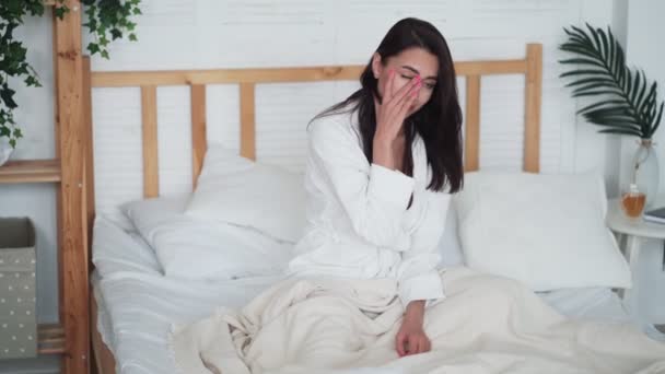 Vrouw werd net wakker, zit op bed, gaap, gefrustreerd dat ze moest opstaan — Stockvideo