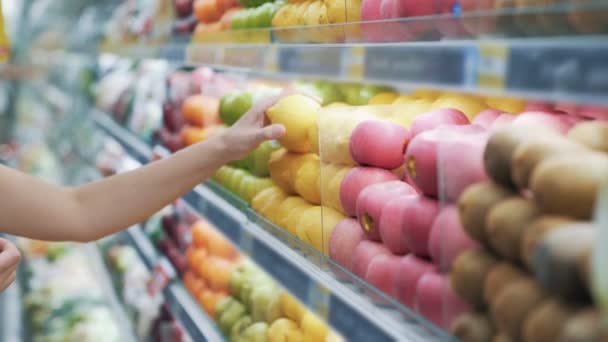 Gros plan, étagère commerciale avec fruits, légumes, l'acheteur prend le citron du comptoir — Video