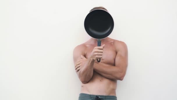 Сексуальный мужчина без рубашки с сковородкой, улыбается, показывает знак ОК, флиртует на камеру — стоковое видео