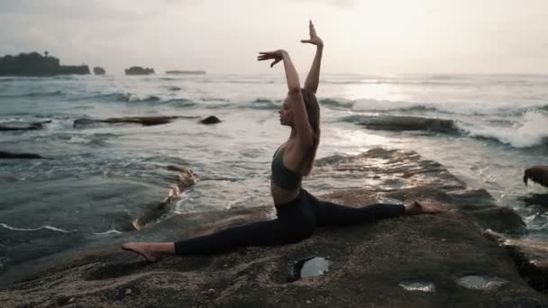 Vrouw doen stretching oefeningen op het strand, oceaan op de achtergrond, slow motion — Stockvideo