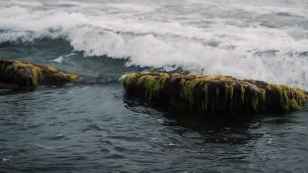 De cerca, vista de las olas del océano estrellándose en el acantilado con salpicaduras y espuma blanca — Vídeo de stock