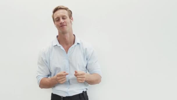 Mann hört Musik mit drahtlosen Kopfhörern, tanzt, bewegt den Kopf im Takt — Stockvideo