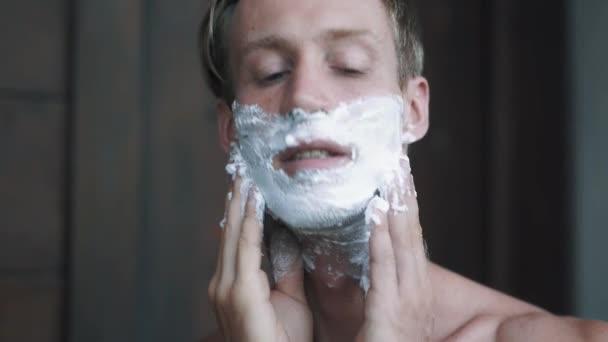 Portrét muže klade pěnu na holení na obličej. — Stock video