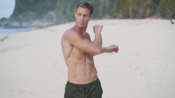 Man with muscular body doing streching exercises on beach, slow motion — Stock Video