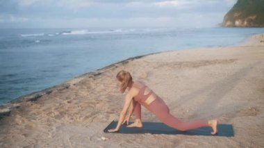 Kadınlar sabahları yavaş çekimde plajda yoga egzersizleri ve esneme hareketleri yapar.