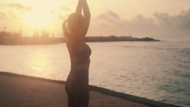 Sylwetka kobiecych ćwiczeń rozciągających się, joga o wschodzie słońca na plaży, zwolnione tempo — Wideo stockowe