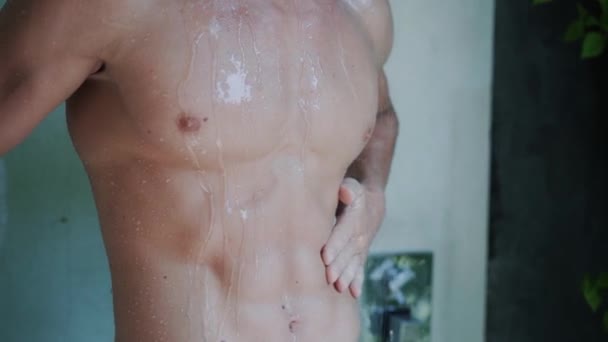 Nahaufnahme des nackten muskulösen Oberkörpers eines Mannes unter der Dusche im Badezimmer, Zeitlupe — Stockvideo