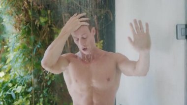 young man with strong body takes refreshing shower at home