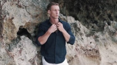 attractive man poses for camera near old limestone rock
